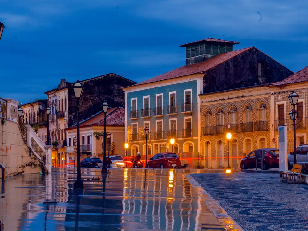 Casarões coloridos do Centro Histórico de São Luís ao anoitecer, com a rua molhada refletindo as luzes