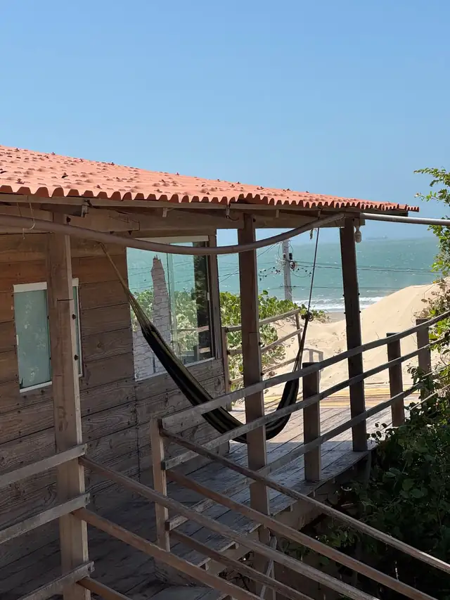 Chalé Pé na Areia por fora, com a rede na varanda e o mar ao fundo